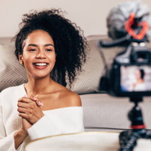 A happy female vlogger live streaming from living room using dslr camera.